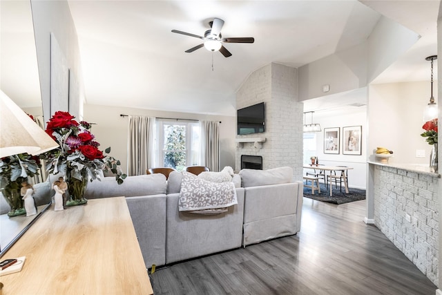 living room with a brick fireplace, a ceiling fan, lofted ceiling, and wood finished floors