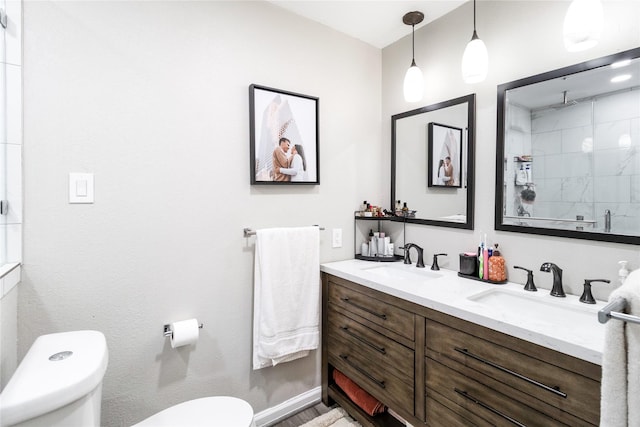 bathroom featuring tiled shower, toilet, and a sink