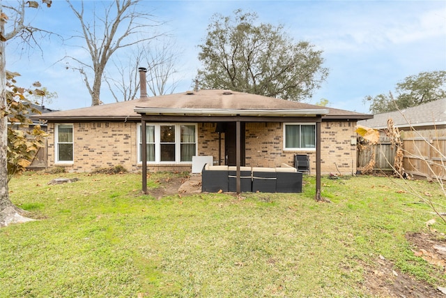 rear view of house with an outdoor living space, a lawn, brick siding, and fence