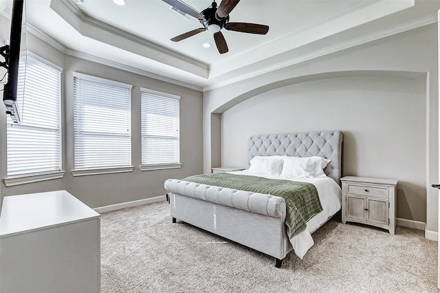 bedroom with ceiling fan, baseboards, a tray ceiling, ornamental molding, and light carpet