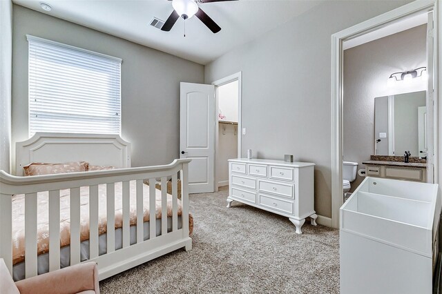 bedroom featuring visible vents, baseboards, light carpet, a ceiling fan, and a sink