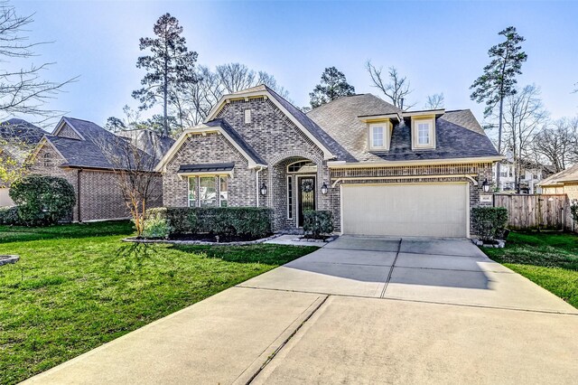 french country home with brick siding, a front lawn, fence, a garage, and driveway