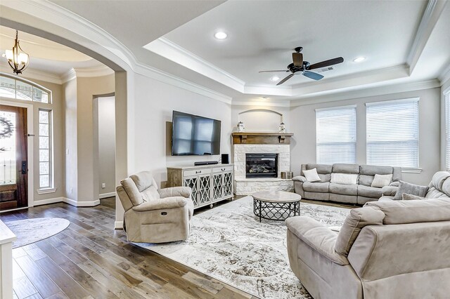 living area with crown molding, baseboards, a fireplace, dark wood-style floors, and a raised ceiling