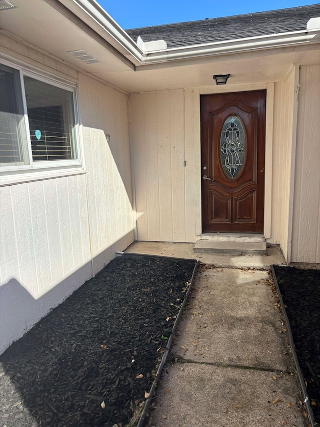 entrance to property featuring a shingled roof