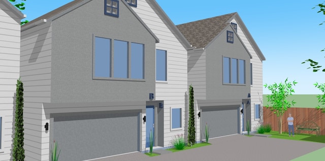 view of front of house featuring decorative driveway, fence, and roof with shingles