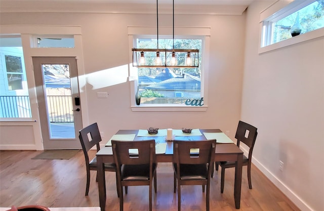 dining room featuring light wood-style flooring, crown molding, and baseboards