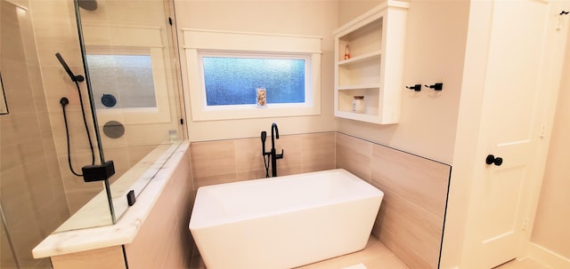 full bath featuring tile walls, a freestanding tub, and a tile shower