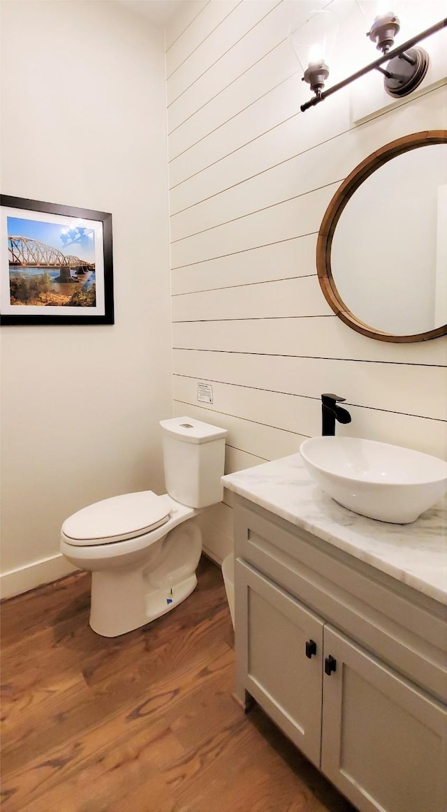 bathroom with toilet, vanity, baseboards, and wood finished floors