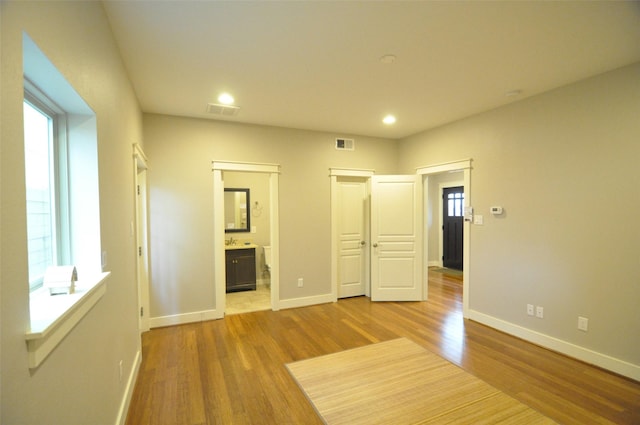 unfurnished bedroom with wood finished floors, visible vents, and baseboards