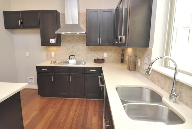 kitchen featuring dark wood-style floors, wall chimney exhaust hood, a wealth of natural light, and a sink