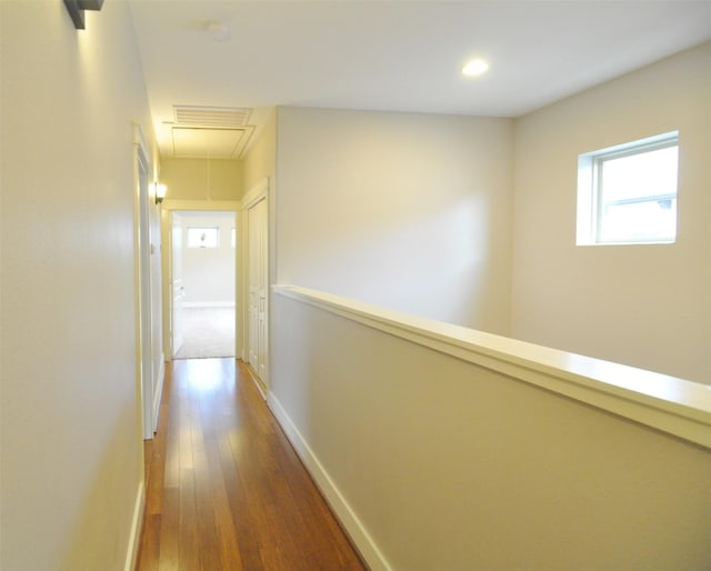 hallway with visible vents, hardwood / wood-style flooring, recessed lighting, baseboards, and attic access