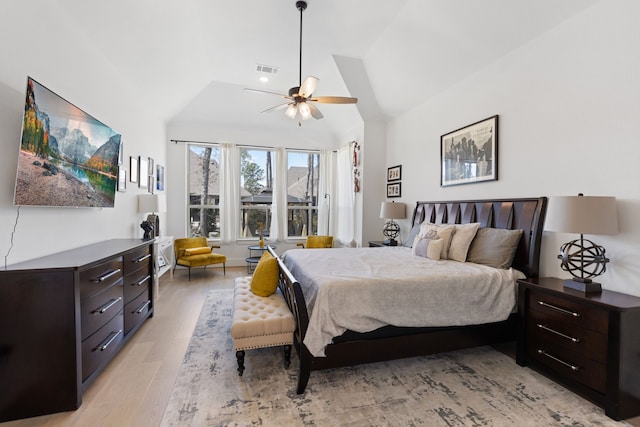 bedroom with light wood finished floors, visible vents, ceiling fan, and lofted ceiling