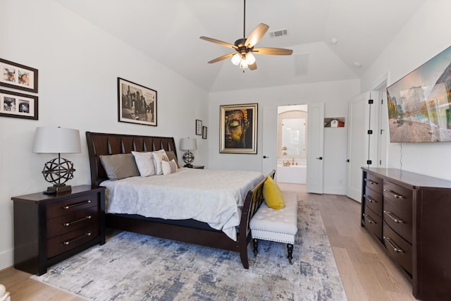 bedroom with visible vents, light wood-style flooring, ensuite bathroom, and vaulted ceiling