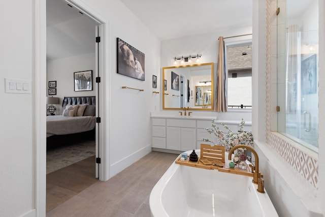 ensuite bathroom with ensuite bathroom, wood finished floors, a shower stall, baseboards, and vanity