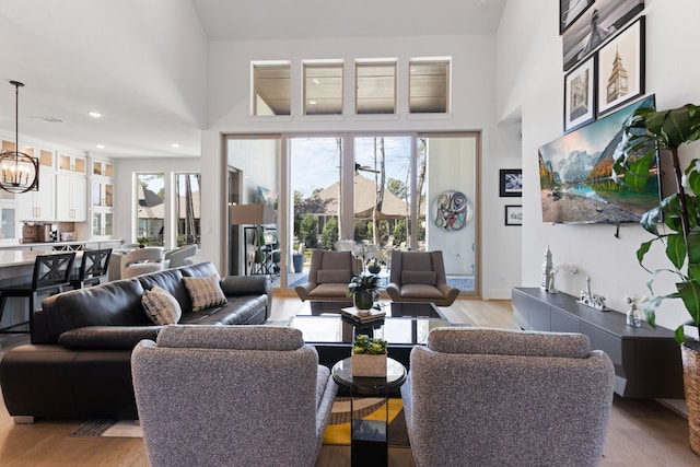 living area featuring a high ceiling, a notable chandelier, and light wood-type flooring