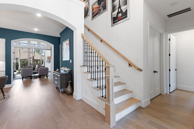 stairway with visible vents, wood finished floors, recessed lighting, arched walkways, and baseboards