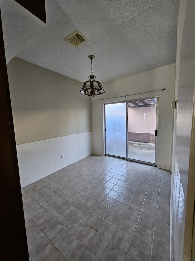 tiled empty room with visible vents, a textured ceiling, and an inviting chandelier