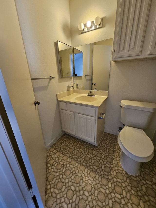 half bath featuring toilet, vanity, and baseboards