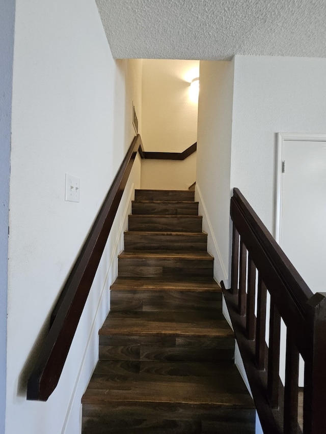 stairs with visible vents, a textured ceiling, and wood finished floors