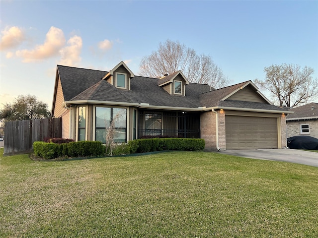 view of front of property with brick siding, concrete driveway, a front lawn, and fence