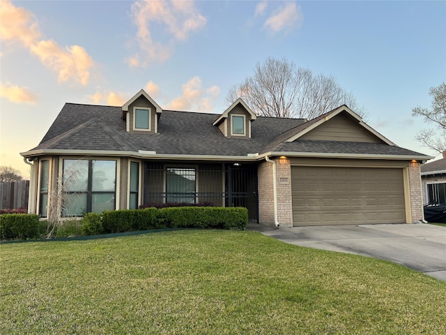 view of front of property with a yard, a shingled roof, concrete driveway, a garage, and brick siding