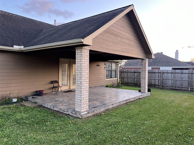 exterior space with a patio area, a yard, fence, and roof with shingles