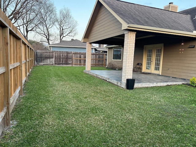 view of yard with a patio area, a fenced backyard, and french doors