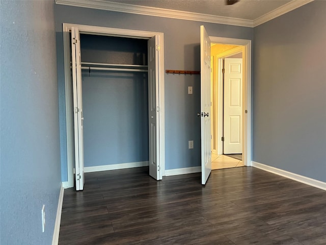 unfurnished bedroom with dark wood finished floors, baseboards, a closet, and ornamental molding