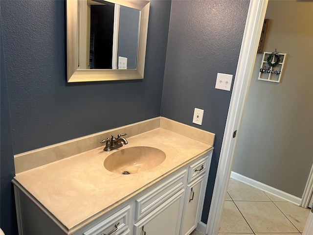 bathroom with tile patterned floors, vanity, baseboards, and a textured wall