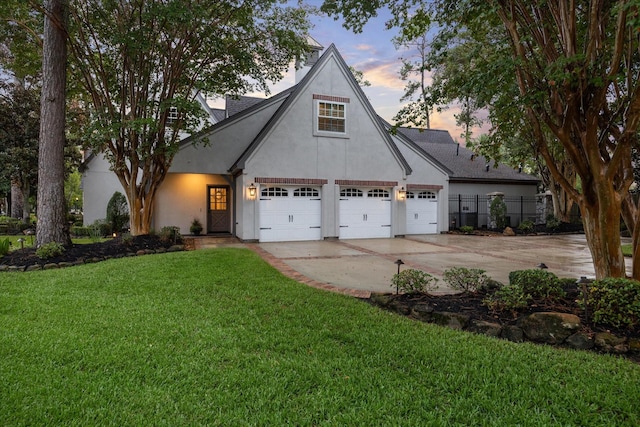 view of front facade featuring a front yard, concrete driveway, fence, and stucco siding