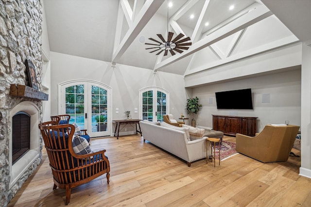 living area featuring hardwood / wood-style floors, a ceiling fan, high vaulted ceiling, a fireplace, and french doors