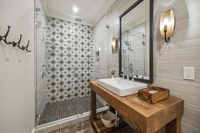 full bath featuring a shower stall, tile walls, visible vents, and a sink