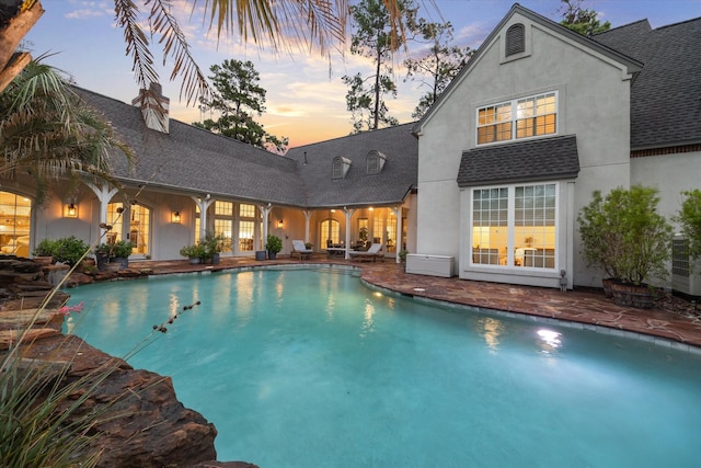 pool at dusk featuring an outdoor pool and a patio area