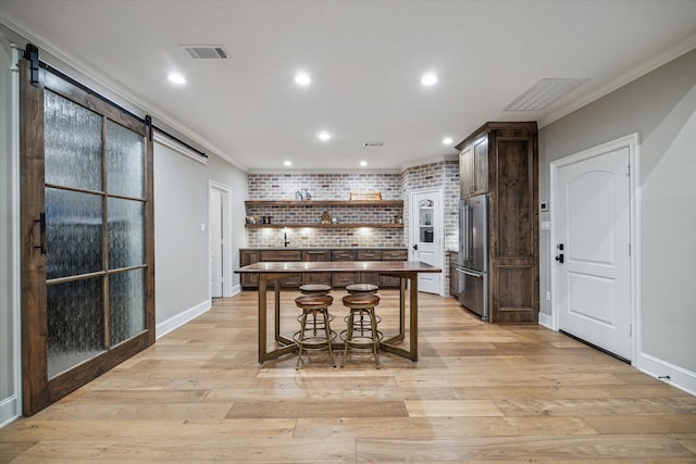 kitchen with visible vents, a kitchen island, a barn door, high quality fridge, and open shelves