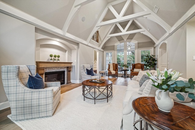 living room featuring visible vents, a premium fireplace, wood finished floors, arched walkways, and high vaulted ceiling