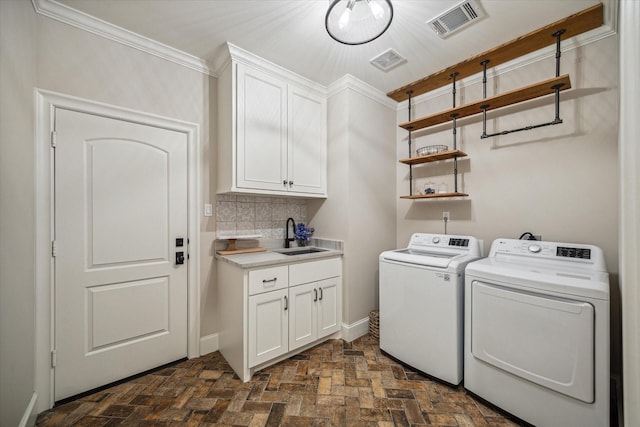 laundry room with visible vents, washer and dryer, brick floor, cabinet space, and a sink