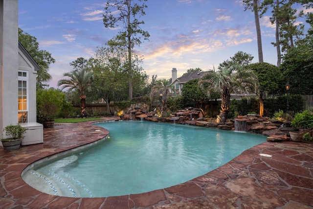 pool at dusk with a fenced in pool, a patio, and a fenced backyard