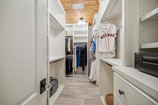 walk in closet with a toaster, visible vents, and wood finish floors