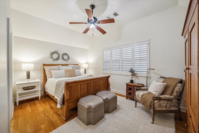 bedroom with light wood-type flooring, visible vents, baseboards, and vaulted ceiling