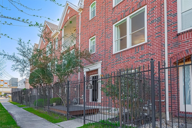 view of property exterior featuring fence and brick siding