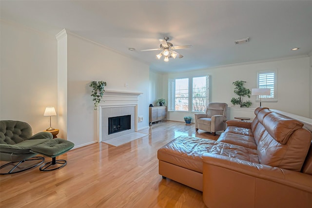 living area with visible vents, a tile fireplace, and ornamental molding