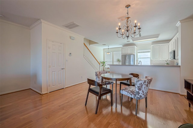 dining room featuring stairway, visible vents, ornamental molding, light wood-style floors, and a chandelier