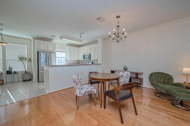 dining space with crown molding, light wood-style floors, and visible vents