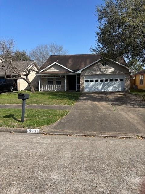 view of front of property featuring a front lawn, a garage, covered porch, and driveway