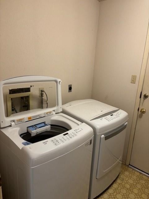 washroom with laundry area, washing machine and dryer, and light floors