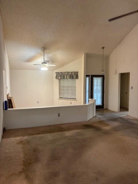 carpeted spare room with a textured ceiling, ceiling fan, and vaulted ceiling