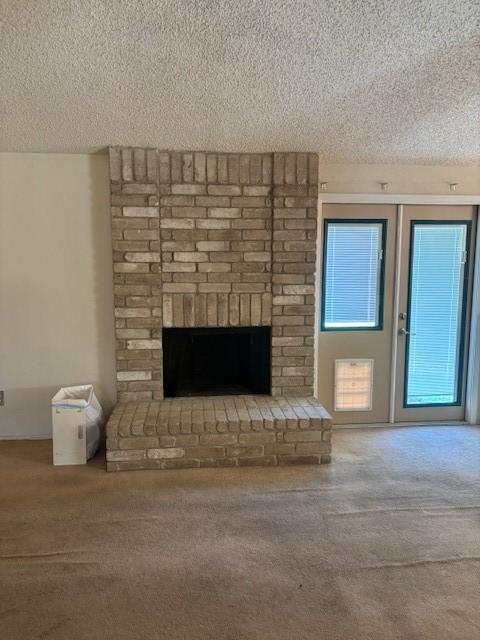 unfurnished living room featuring carpet flooring, a textured ceiling, and a fireplace