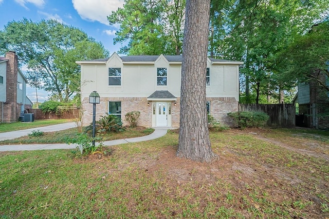 view of front facade featuring cooling unit, fence, stucco siding, a front lawn, and brick siding