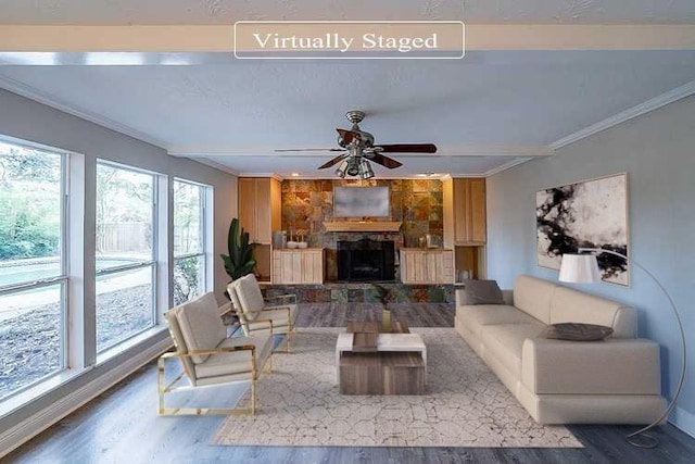 living area with ceiling fan, crown molding, wood finished floors, and a fireplace with raised hearth