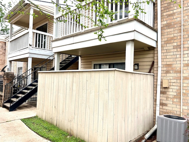 view of home's exterior featuring central air condition unit, stairway, and brick siding